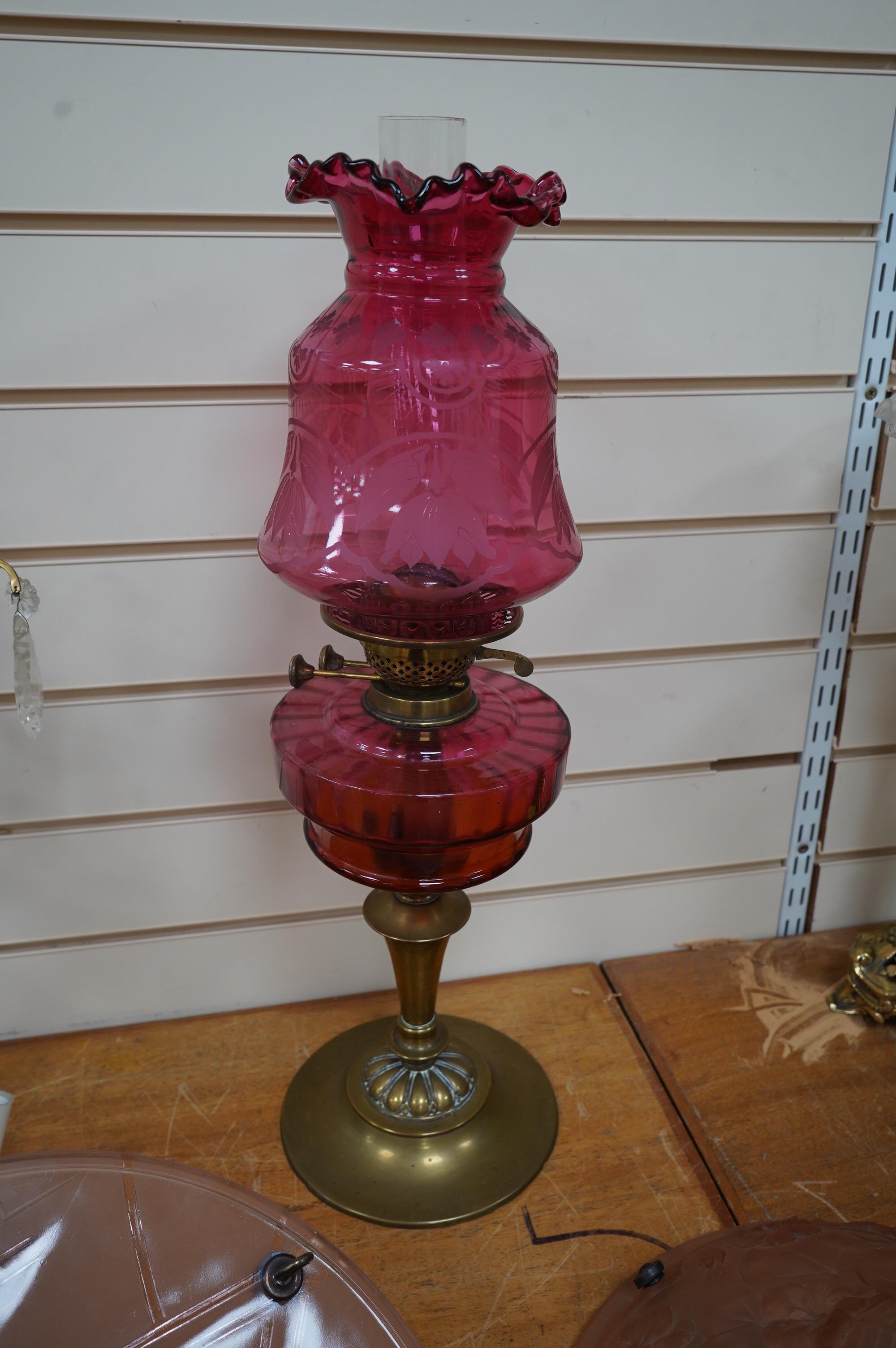 A Victorian oil lamp on brass base with cranberry font, acid etched cranberry shade chimney, overall 62cm high. Condition - good